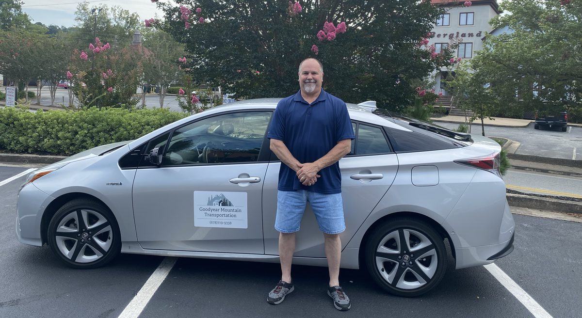 Jim Goodyear standing beside his silver 2018 Toyota Prius Touring in downtown Helen